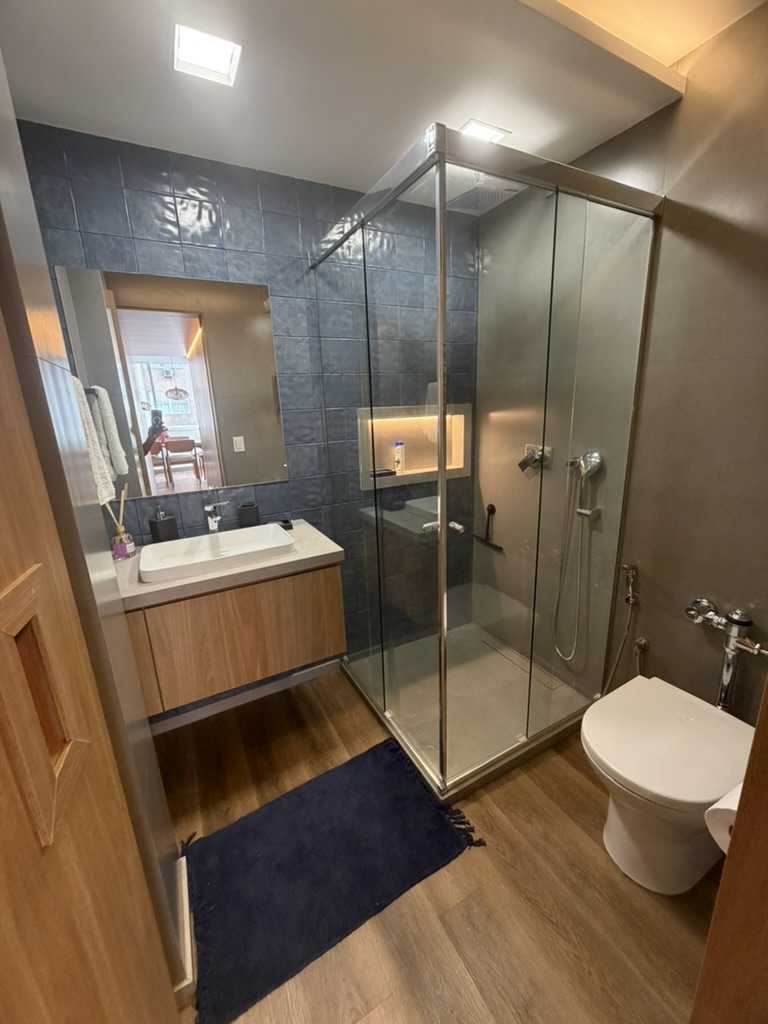 Bathroom with glass shower, sink and dark tiled wall