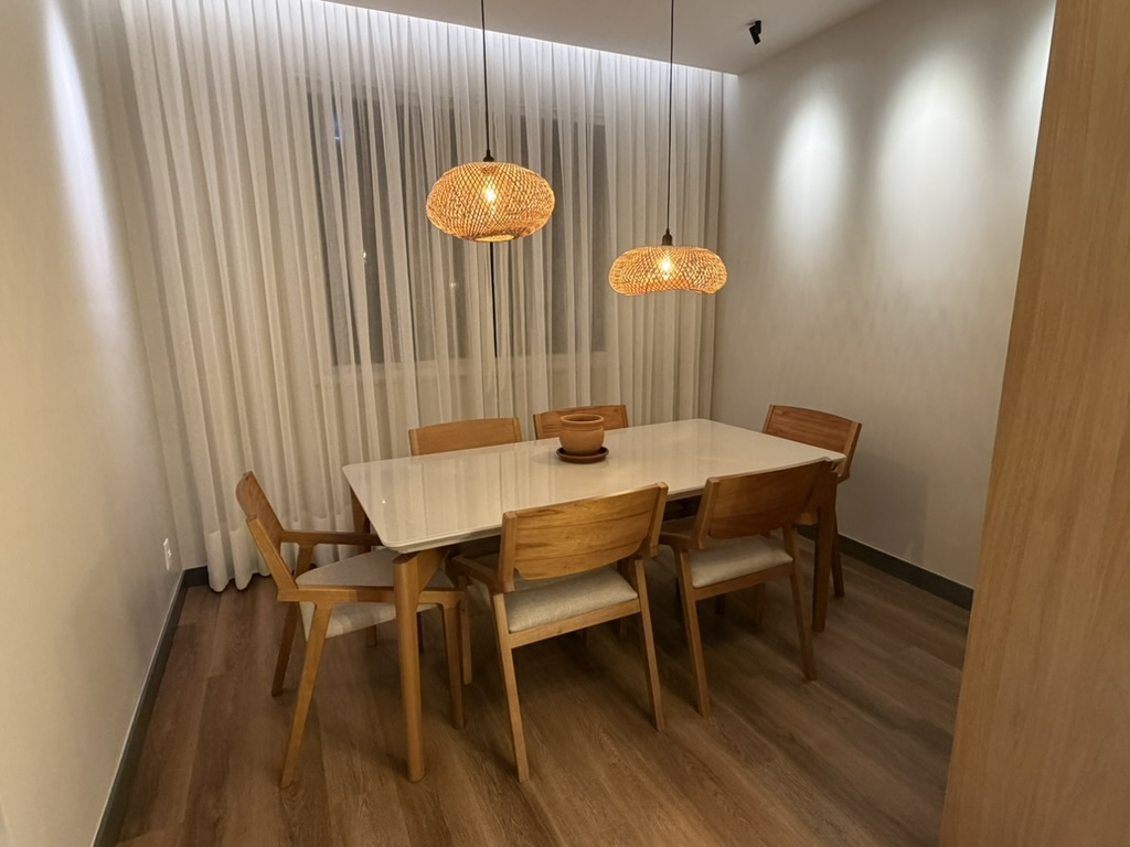 Dining room at night with two woven pendant lights and wood chairs